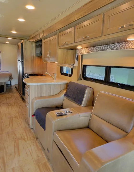 Comfortable rv rental interior: kitchen with sink & microwave, and cozy recliners. Perfect for travel and relaxation.. Entegra Coach Vision 2019