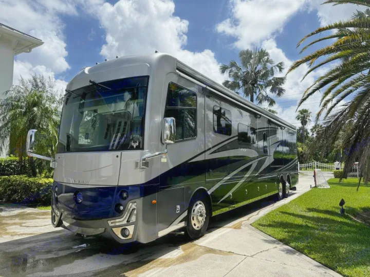 Stunning luxury RV rental, a silver and blue motorhome, parked on a sunny driveway with palm trees. Perfect for travel!. Holiday Rambler Armada 2022