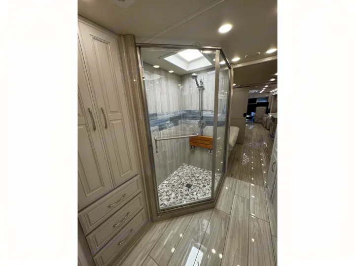 Elegant RV rental interior: large shower with glass, skylight, wooden seat, and sleek cabinets. Modern design for comfortable travel.. Holiday Rambler Armada 2022