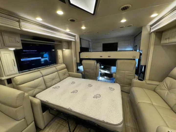 Modern RV rental interior: living area with sofa bed, TV, and cockpit. Enjoy comfortable travels!. Holiday Rambler Armada 2022
