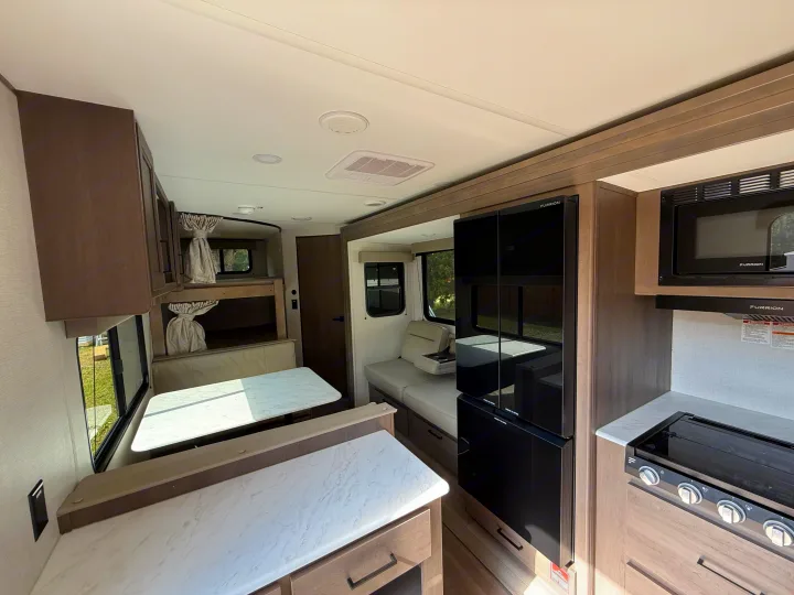 This RV rental's interior boasts a modern kitchen with a large fridge, cozy dinette, and convenient bunk beds for travel.. Transcend 26BHX 2025