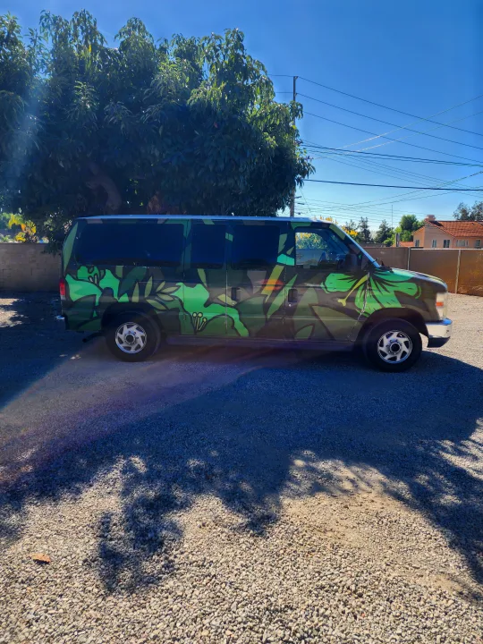 Vibrant green leafy van, great for an RV rental, parked on gravel under a clear sky next to a large tree.. Escape Trailer Industries E150 XLT 2011