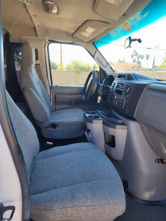 RV rental van's clean front cabin, showcasing grey seats, a functional dashboard, and steering wheel.. Escape Trailer Industries E150 XLT 2011