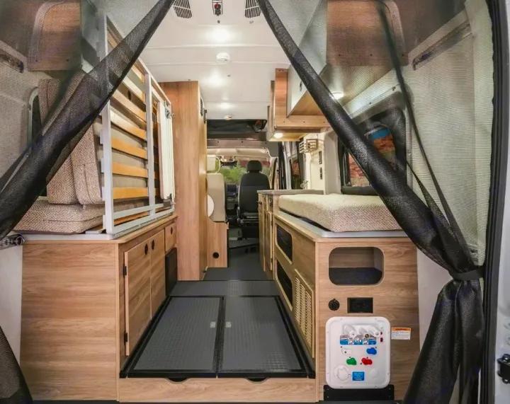 Explore this RV rental's versatile camper van interior, featuring a convertible bed, organized storage, and a utility panel.. Winnebago Solis 2025