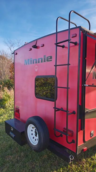 Back of a red Minnie travel trailer with a ladder and spare tire, ideal for your next RV rental adventure.. Minnie Minnie Trailer 2019