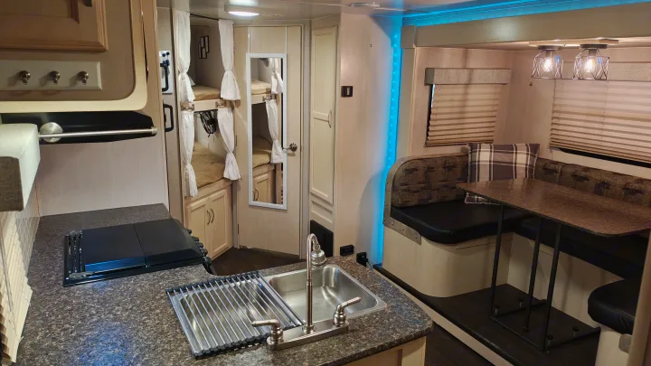 This RV rental interior features a functional kitchenette, a comfortable dinette, and cozy bunk beds, ideal for family travel.. Minnie Minnie Trailer 2019