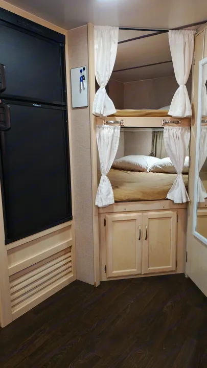 RV rental interior featuring a Dometic fridge, cozy bunk beds with privacy curtains, and storage cabinets.. Minnie Minnie Trailer 2019