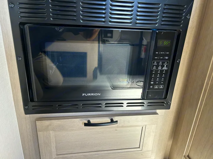 Black Furrion microwave/convection oven in an RV rental kitchen, with a digital display showing '55' and control buttons on the right.. Forester LE 2026