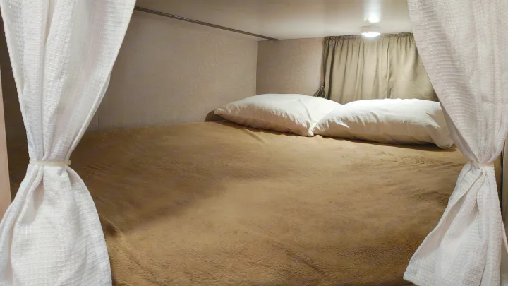 Inside a cozy rv rental: a bunk bed with soft white pillows and a warm brown blanket, framed by curtains.. Minnie Minnie Trailer 2019