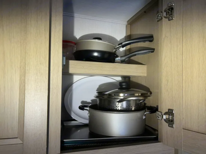 Compact kitchen cabinet in an RV rental, showing neatly stacked pots, pans, and dishes. Essential cooking storage.. Forester LE 2026