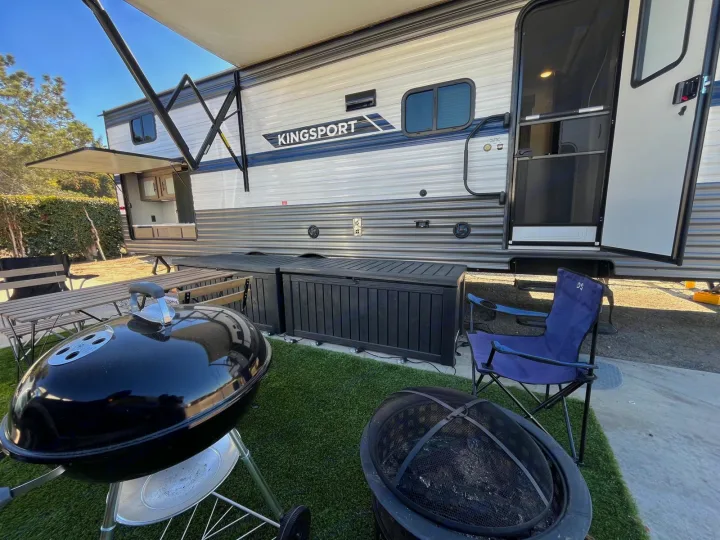 RV rental ready for fun! A travel trailer with an outdoor kitchen, grill, fire pit, picnic table, and storage on artificial grass.. Gulf Stream Kingsport 2023
