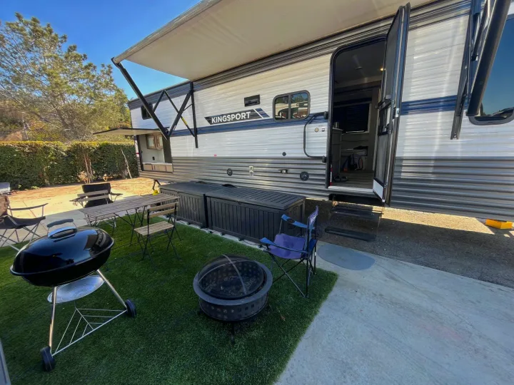 Kingsport RV rental with extended awning, outdoor kitchen, grill, and fire pit on a lush patio. Ready for your adventure!. Gulf Stream Kingsport 2023
