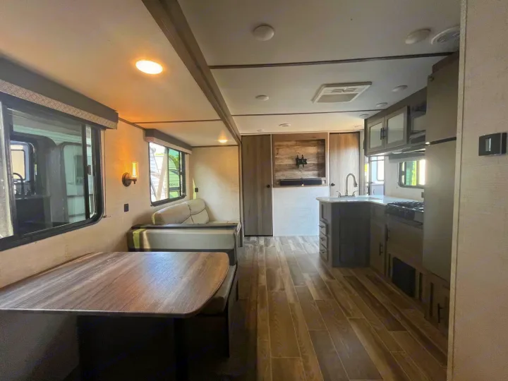 Explore this modern rv rental interior with a dining booth, full kitchen, wood flooring, and ample light from multiple windows.. Gulf Stream Kingsport 2023
