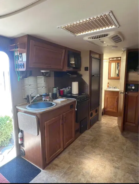 RV rental interior: A well-equipped kitchen featuring a sink, stove, microwave, fridge, and an adjacent bathroom.. Lance Manufacturing Lance Manufacturing Trailer 2016