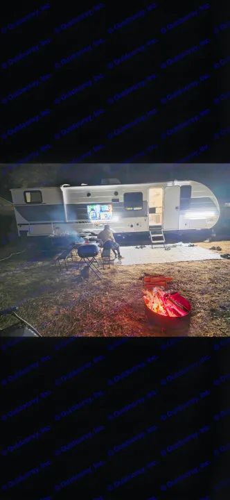 Night camping in an RV rental! Enjoying an outdoor TV, grilling by the trailer, and a warm campfire under the stars.. Forest River Wildwood X-Lite 2026