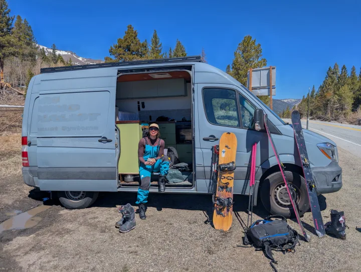 RV rental adventure: woman in ski gear by her camper van, surrounded by skis, snowboard, and mountain views.. Mercedes-Benz Sprinter 2014