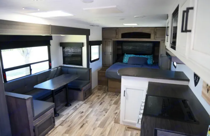 Modern RV rental interior showing a dinette, kitchen, and bedroom with contemporary finishes and light wood flooring.. Venture Venture Trailer 2023