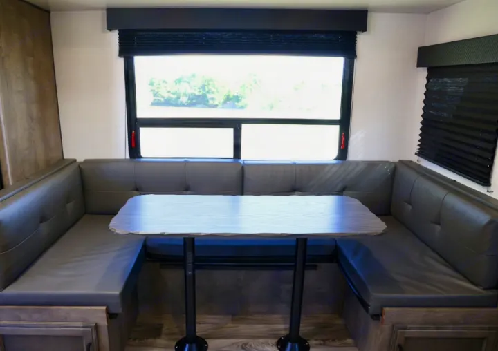 This RV rental offers a U-shaped dinette with gray cushions, a light table, and large windows, perfect for dining and views.. Venture Venture Trailer 2023