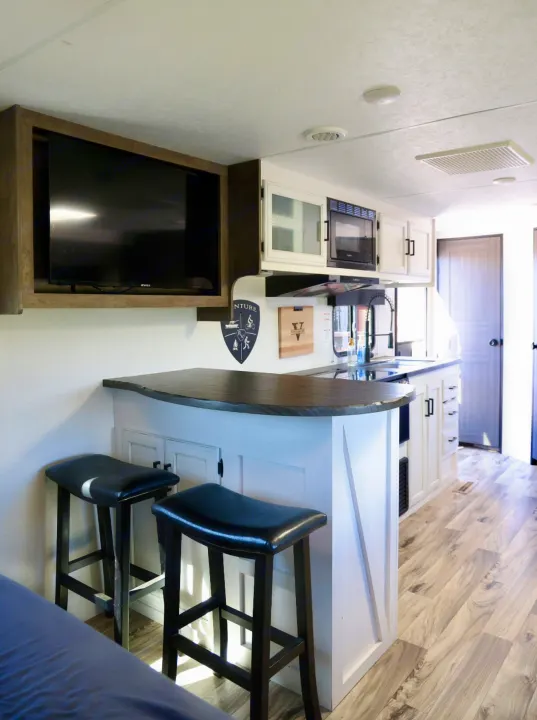 Experience comfort in this modern rv rental! Features a stylish kitchen bar, stools, and wall-mounted TV.. Venture Venture Trailer 2023