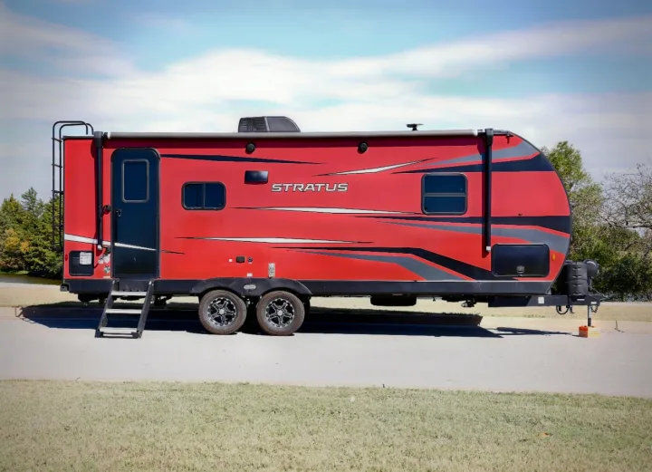 Vibrant red Stratus travel trailer for RV rental, featuring black/grey graphics, parked on asphalt under a blue sky.. Venture Venture Trailer 2023