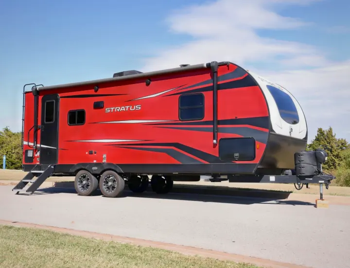 This striking red and black Stratus RV rental, with large windows and sturdy wheels, is parked outdoors, ready for adventure.. Venture Venture Trailer 2023