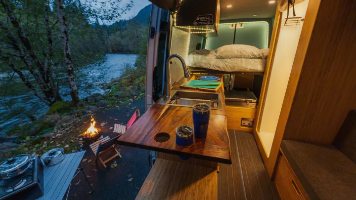 This cozy rv rental camper van kitchen and bedroom open to a riverside campfire. Perfect for outdoor adventure and van life!. Mercedes Sprinter 2017