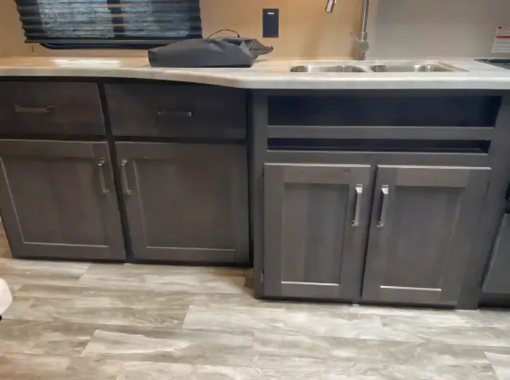 Modern rv rental kitchen with dark gray cabinets, a double sink, and a light-toned countertop.. Grand Design Transcend Xplor 2022