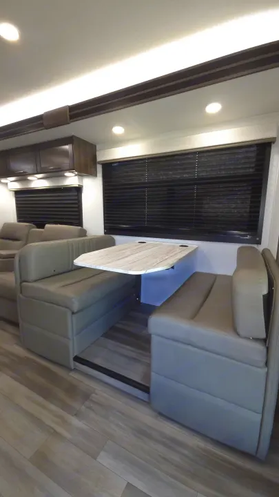 Modern rv rental interior: dinette with gray upholstered seating, marble-look table, sleek blinds, and recessed lighting.. Entegra Coach Odyssey 25R 2026