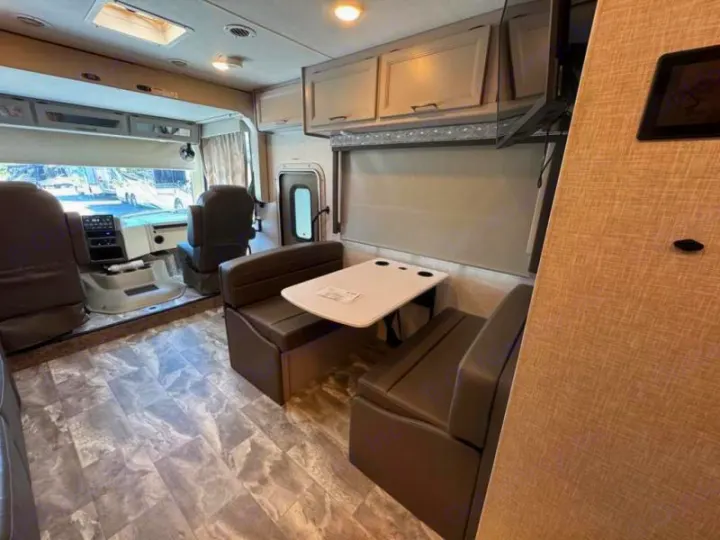Explore this rv rental's spacious interior: front cockpit, comfortable dinette with booth seating, and overhead cabinets.. Thor Windsport 2023
