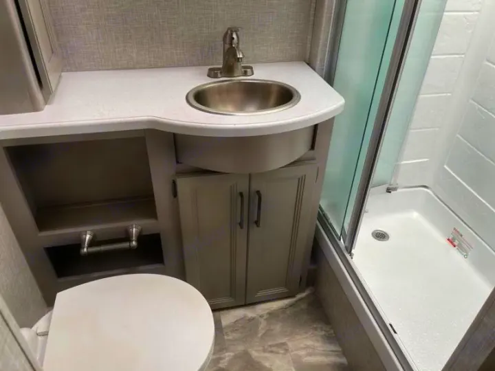 Compact RV rental bathroom: vanity with sink, toilet, & enclosed shower. Practical for travel trailers/motorhomes.. Thor Windsport 2023