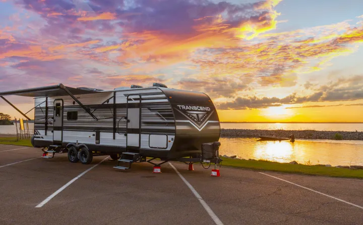 Scenic rv rental parked at sunset by a lake, perfect for camping and outdoor adventures.. Grand Design Transcend Xplor 2023