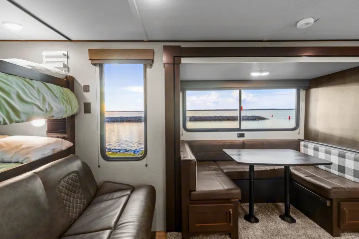 This RV rental offers a practical interior with bunk beds, a comfortable dinette, and large windows revealing beautiful water views.. Grand Design Transcend Xplor 2023