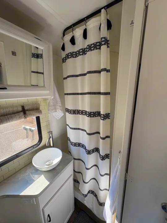 This RV rental features a bright, modern bathroom with a vessel sink, subway tile, and a decorative black & white shower curtain.. Itasca Spirit 1996