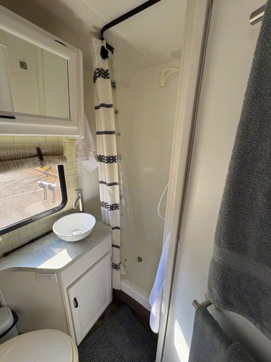 RV rental bathroom: modern sink, tiled backsplash, cozy shower with curtain, and toilet for on-the-go comfort.. Itasca Spirit 1996