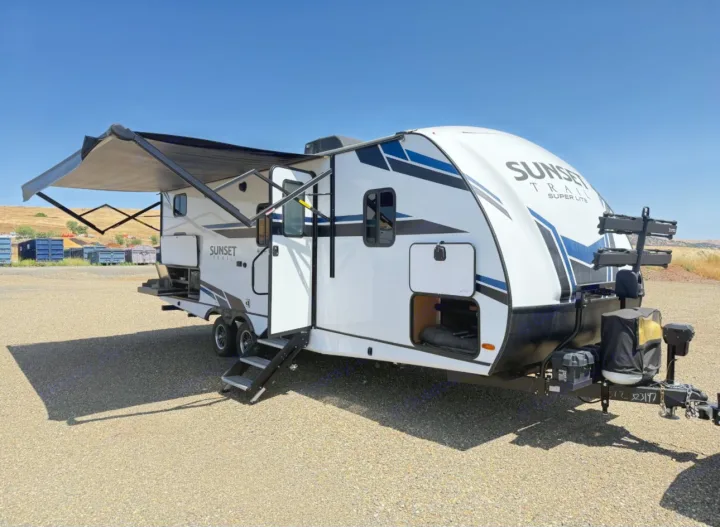 White Sunset Trail Super Lite travel trailer rv rental. Awning extended, steps down, and storage open. Ready for your adventure.. Crossroads RV Sunset Trail Super Lite 2021