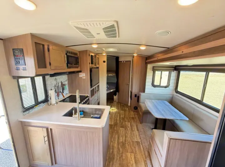 Spacious rv rental interior with modern kitchen, U-shaped dinette, and light wood finishes, ideal for travel.. Crossroads RV Sunset Trail Super Lite 2021