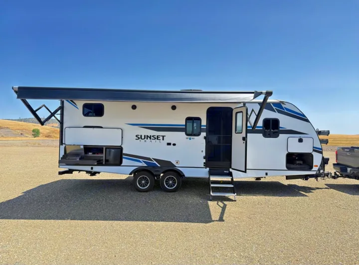A white and blue RV rental travel trailer with an extended awning and an outdoor kitchen for camping adventures.. Crossroads RV Sunset Trail Super Lite 2021