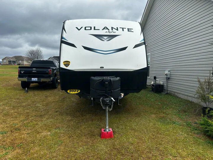 A 2022 Volante Lite RV, ideal for an rv rental, parked in a grassy yard next to a house, with a black pickup truck.. Crossroads RV Volante 2022