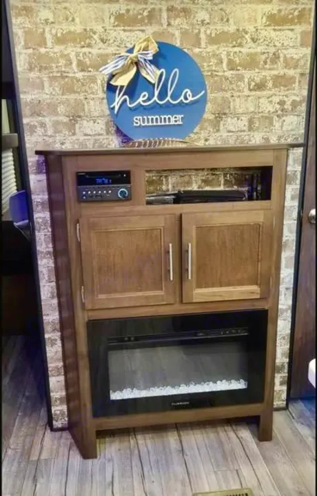 RV rental interior featuring a cozy entertainment center with a stereo, electric fireplace, and storage, plus a "hello summer" sign.. Forest River Cherokee 2019