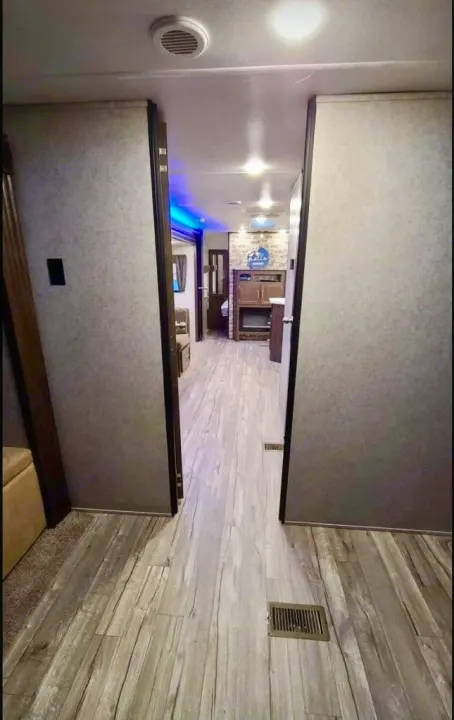 RV rental's inviting hallway, featuring modern wood-look flooring and a peek into the living area with ambient lighting.. Forest River Cherokee 2019