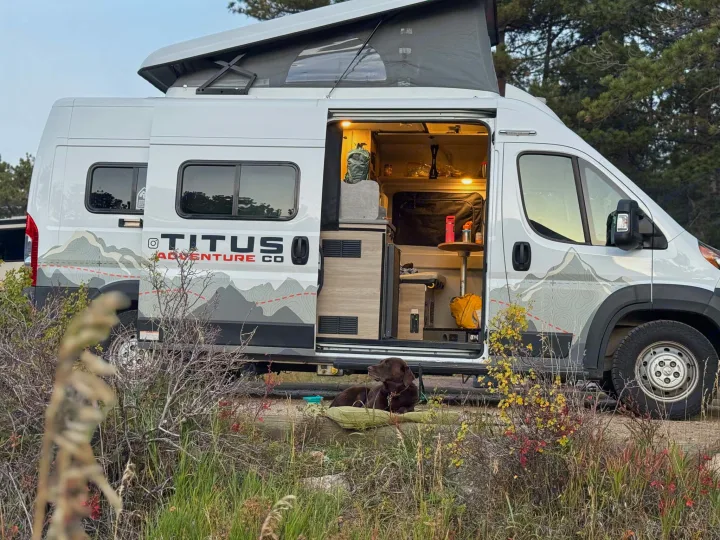 Cozy Titus Adventure Co RV rental with a pop-top open, dog resting outside. Perfect for camping and exploring nature.. Winnebago Solis 2022