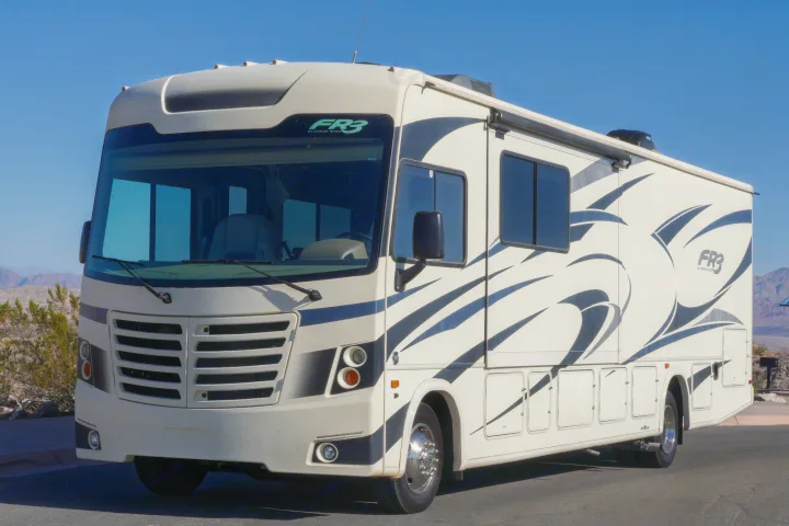 A large, cream Class A motorhome, a Forest River FR3 rv rental, with blue graphics, parked under a clear blue sky.. FR3 FR3 Motorhome 2019