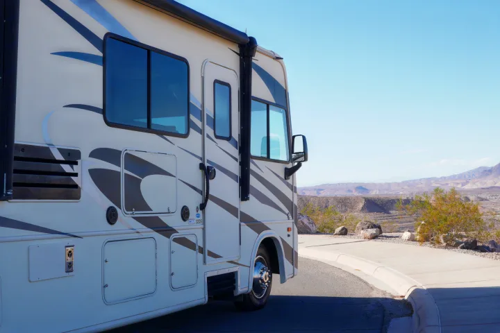 This RV rental, a motorhome with striped decals, is parked at a scenic desert overlook with mountains under a clear blue sky.. FR3 FR3 Motorhome 2019
