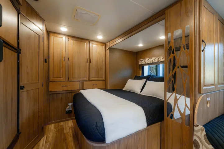 Cozy RV rental bedroom with warm wooden interiors, built-in storage, and a comfortable bed. Ideal for compact living.. Coachman Prism 2200 LE 2017