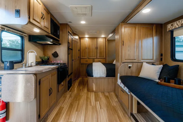 Bright RV rental interior showing a well-equipped kitchen, comfortable dinette, and cozy bed.. Coachman Prism 2200 LE 2017