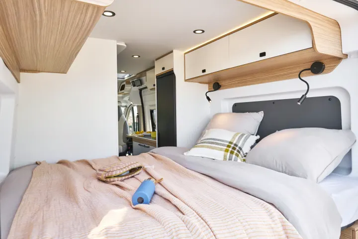 Cozy RV rental bedroom with comfortable bedding, reading lights, and ample storage, perfect for your next adventure.. PILOTE V600G 2026
