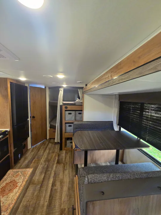 This inviting rv rental features a cozy dinette, bunk beds with privacy curtains, and wood-look flooring. Bright and functional.. Forest River Campsite Reserve 2025
