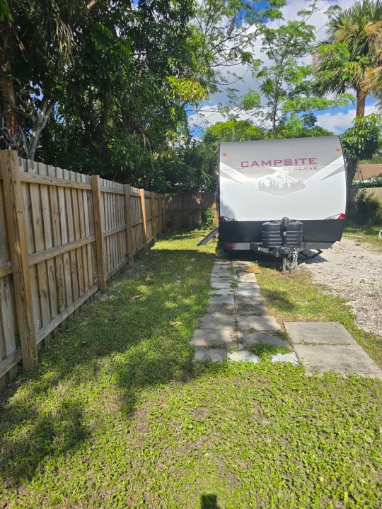 Campsite Reserve RV rental parked by a fence and lush trees. Ideal for outdoor adventures and comfortable travel.. Forest River Campsite Reserve 2025