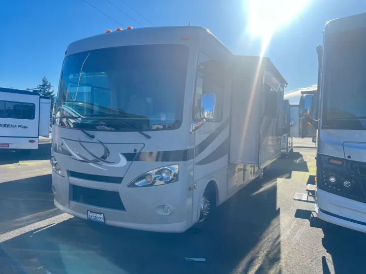 Sun-drenched light grey Hurricane RV rental with an extended slide-out, parked outdoors on a bright day.. Thor Hurricane 2014