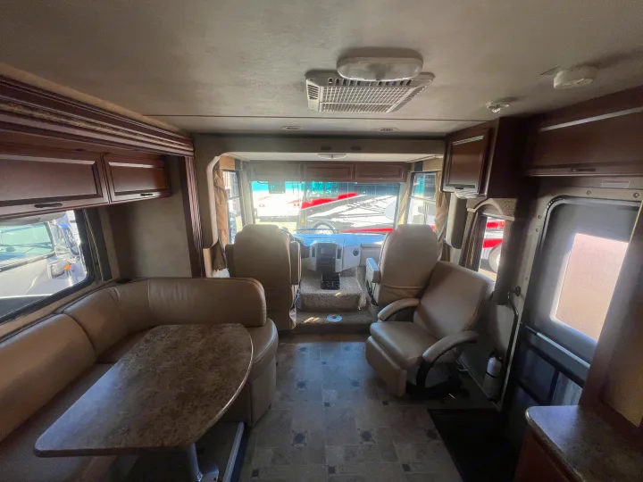 This RV rental interior features an inviting living space with a dinette, comfy recliner, and a well-equipped driver's cockpit.. Thor Hurricane 2014